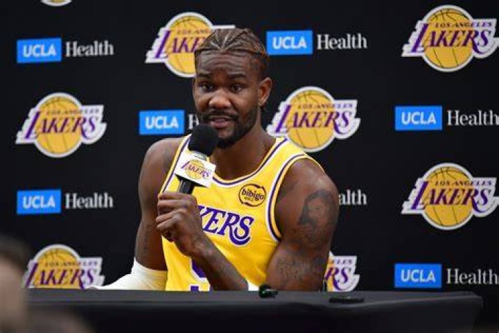 a man in a lakers jersey is holding his hands above his head and