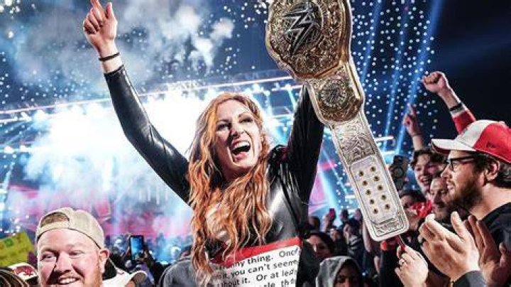 Becky Lynch holding two title belts