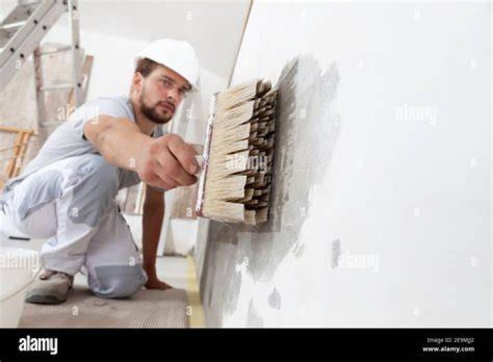 Construction Worker restores wall and paints in a home